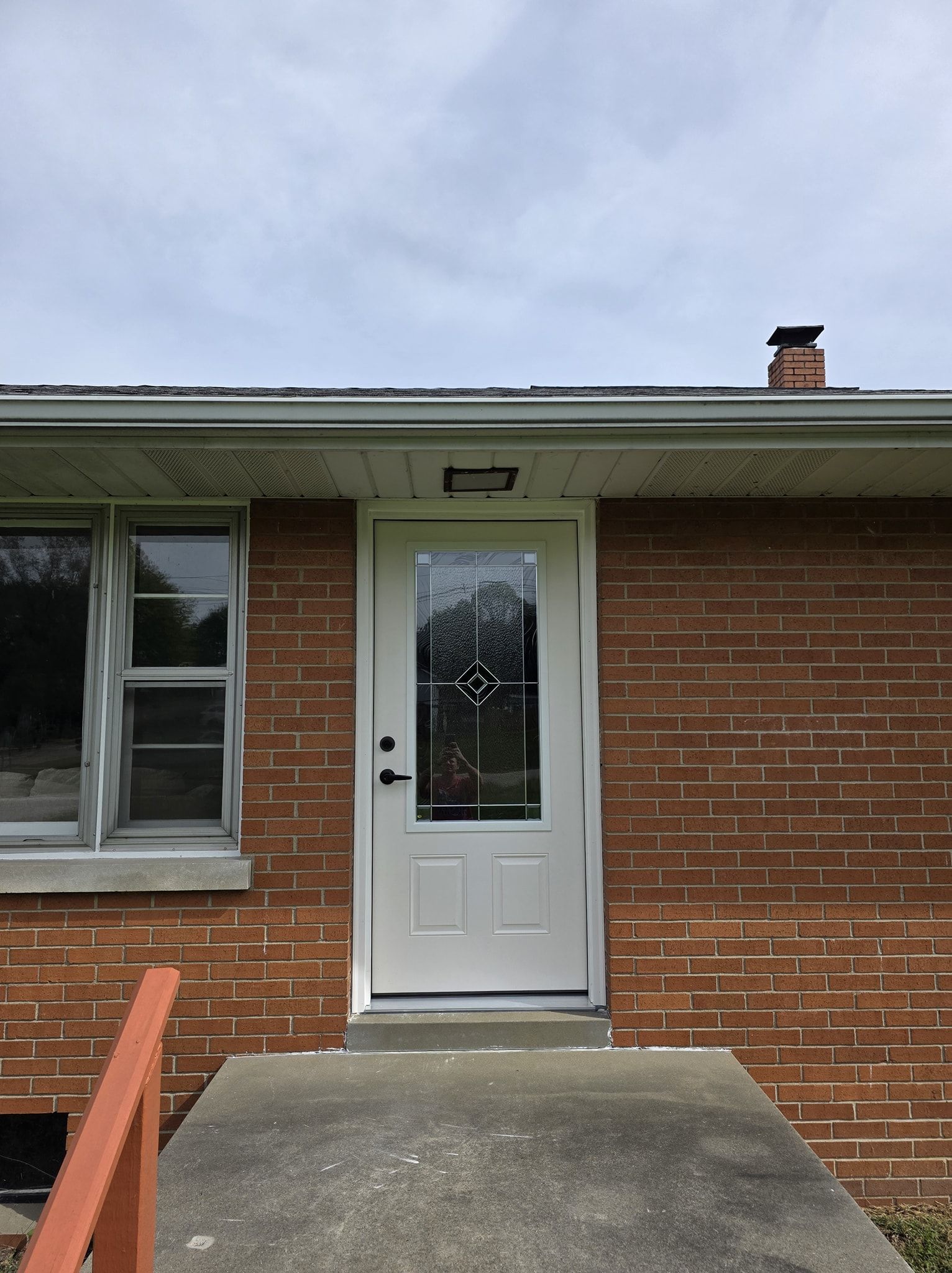 White door with glass panel on a brick building with a concrete step.