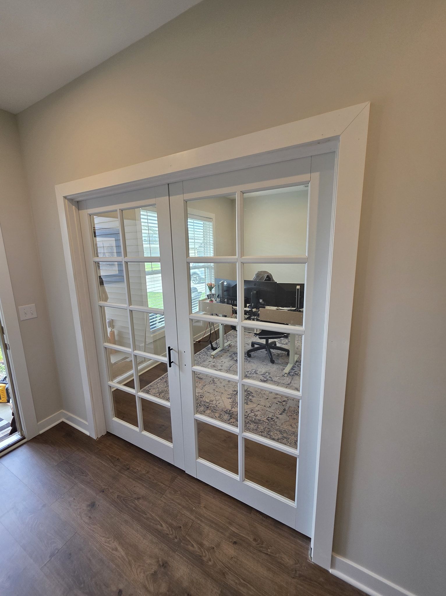Double glass pane doors with white trim, open to a room with a desk and chair.