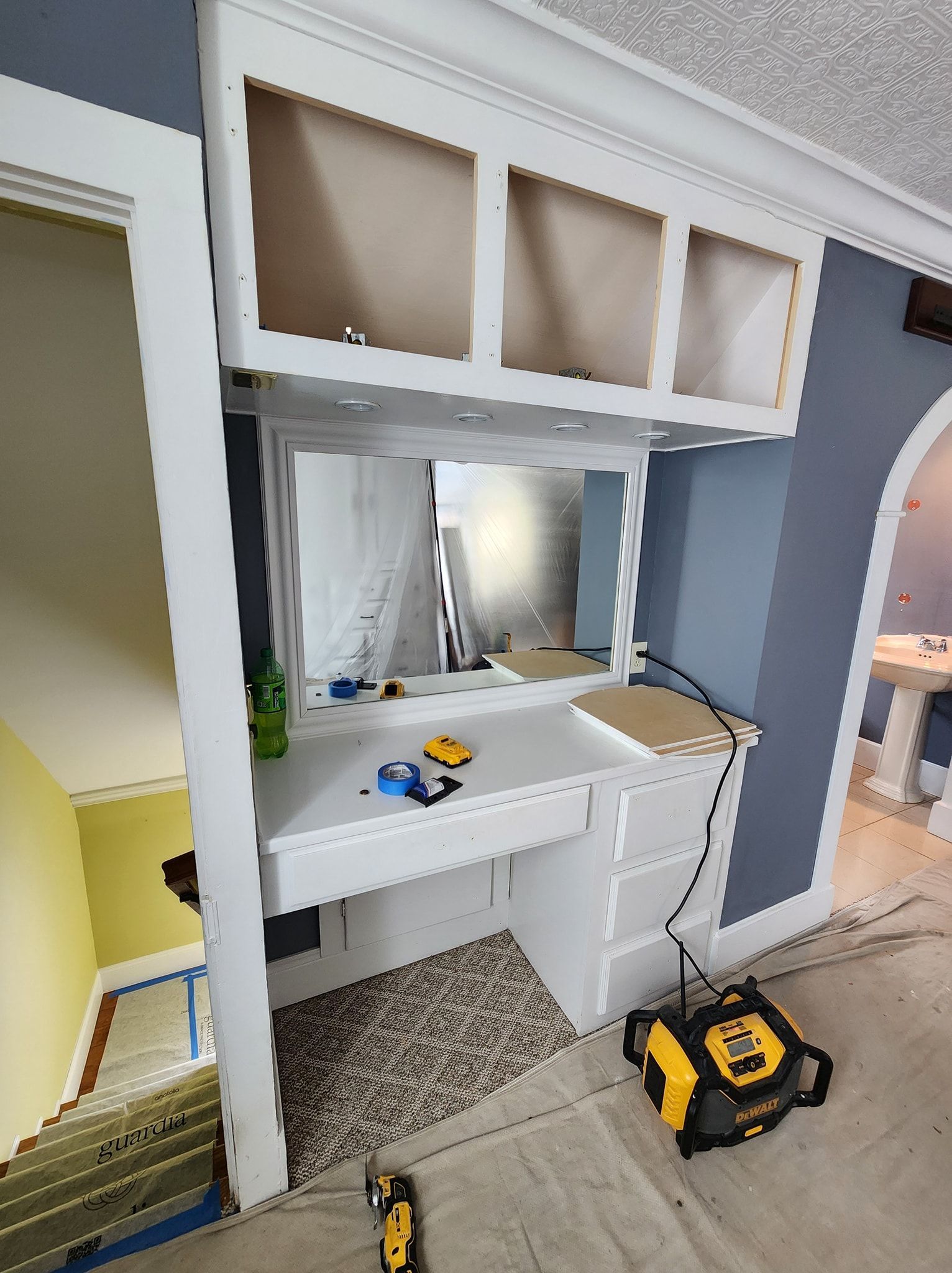Vanity nook with unfinished cabinets, mirror, and work in progress.
