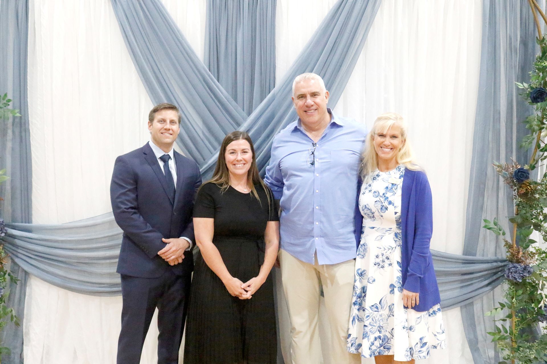 Group of people standing in front of a sign with a tree logo.