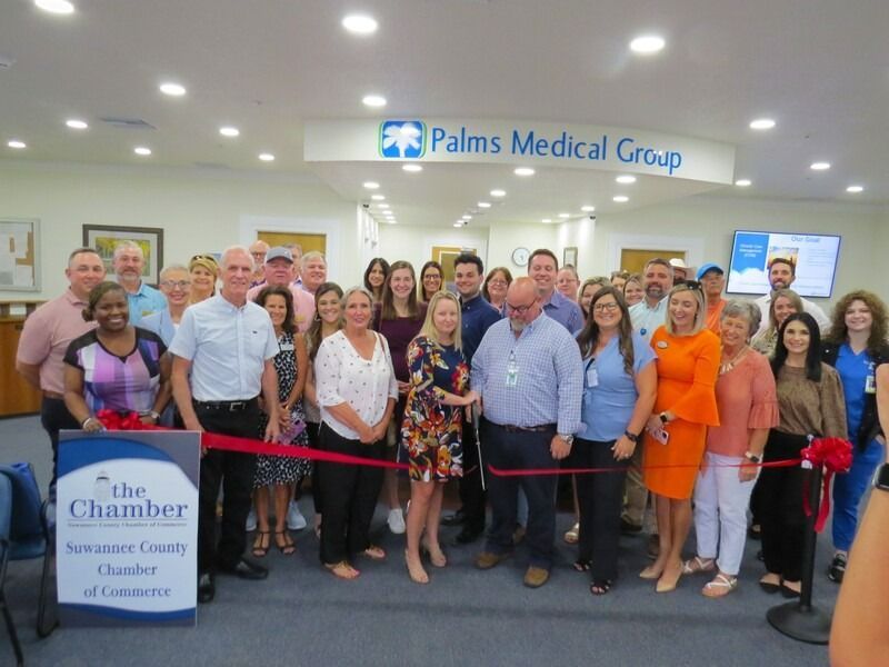 Group of people cutting a ribbon at a Palms Medical Group Chamber event.