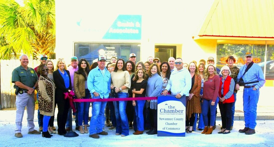 Group of people cutting a ribbon in front of a building; 