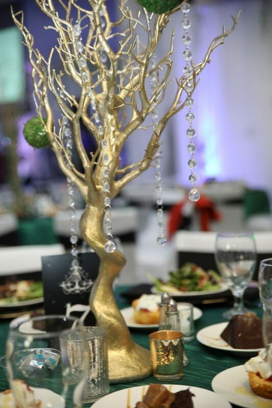 Gold tree centerpiece with hanging crystals on a table set for a formal event.
