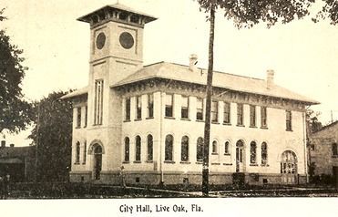 City Hall in Live Oak, Florida. Two-story building with clock tower and numerous windows.