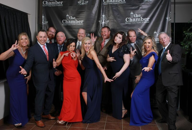 Group of people posing with playful expressions in front of a backdrop that reads 
