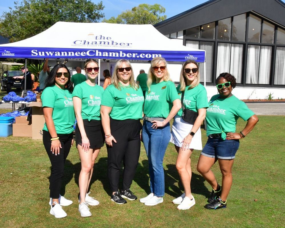 Group of people wearing green shirts in front of a tent that says 
