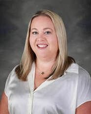 Woman with blonde hair wearing a white top smiling at the camera.