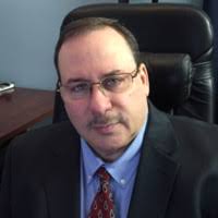 A man in a suit and tie is sitting in an office chair.