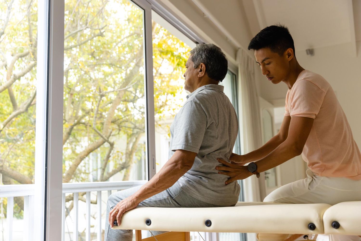 A man is giving an older man a massage on a table.