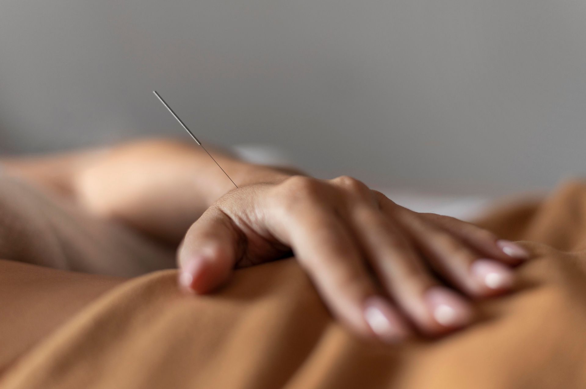 A close up of a person 's hand holding an acupuncture needle.