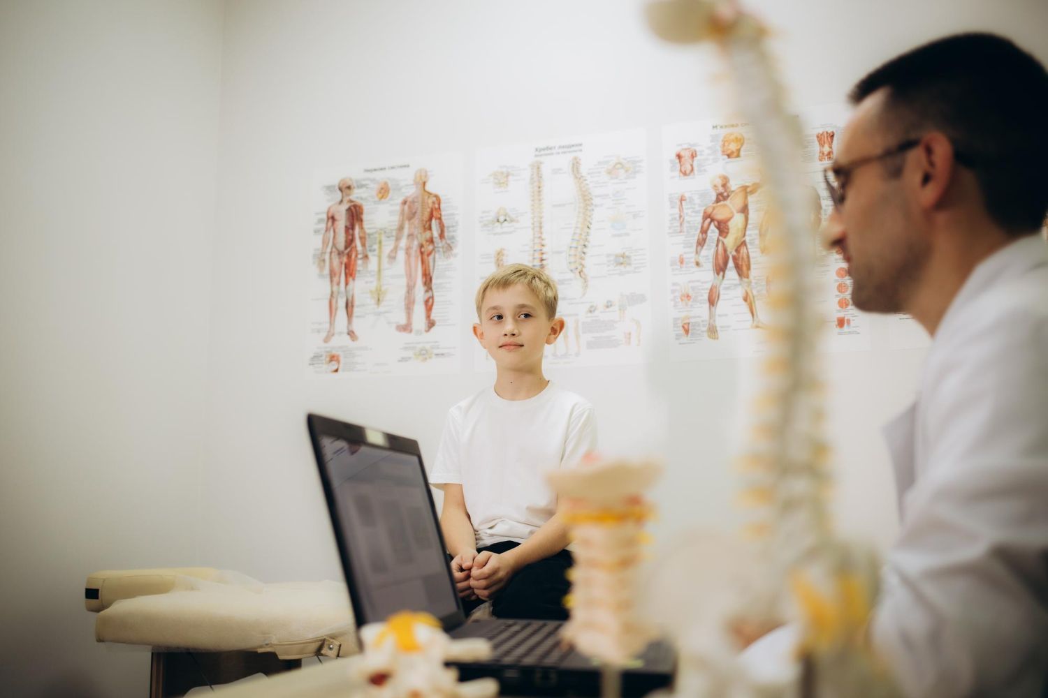 A young boy is sitting at a table talking to a doctor.