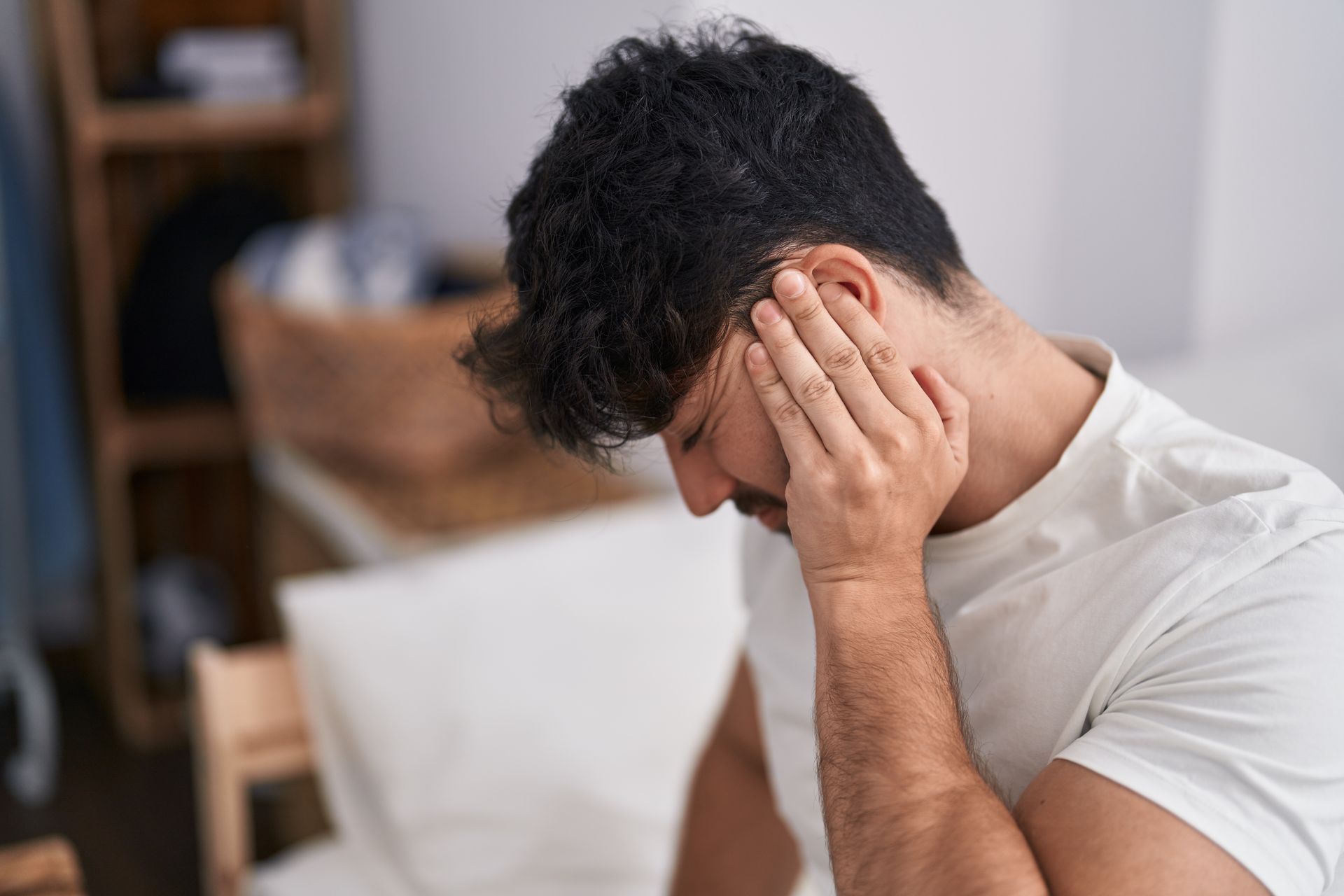 Person holding their head in distress while sitting indoors on a couch