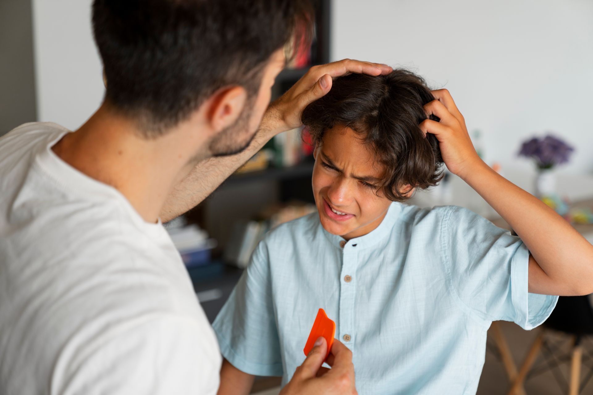 A man is scratching a boy 's head with a red card.