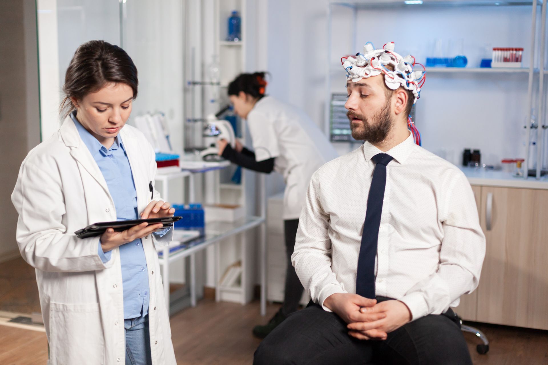 A man is sitting in front of a female doctor wearing a headband.