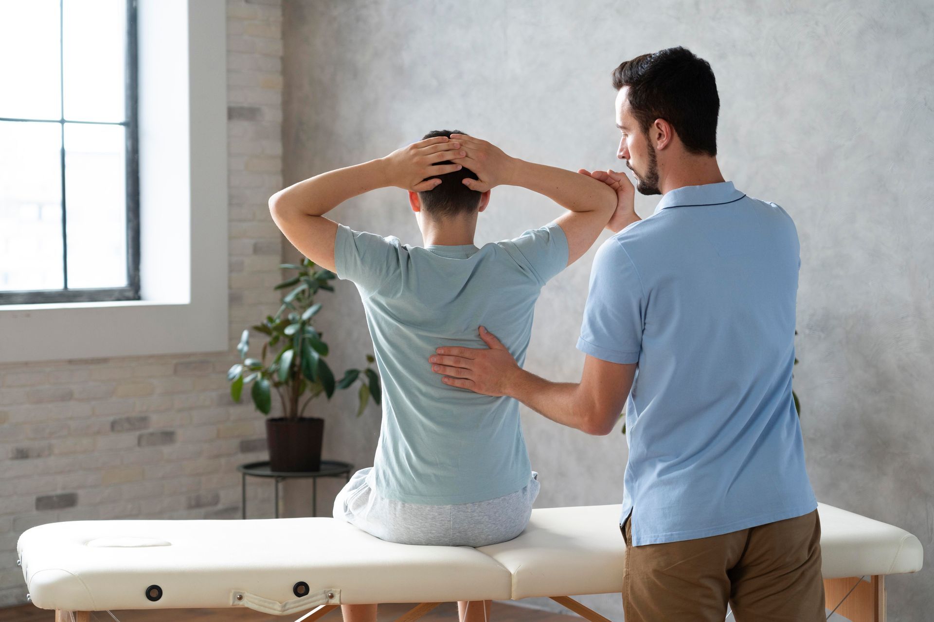 Physical therapist assisting a patient stretching on a treatment table in a bright clinic room