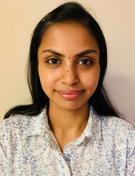 Gayathri in a white shirt is smiling for the camera.