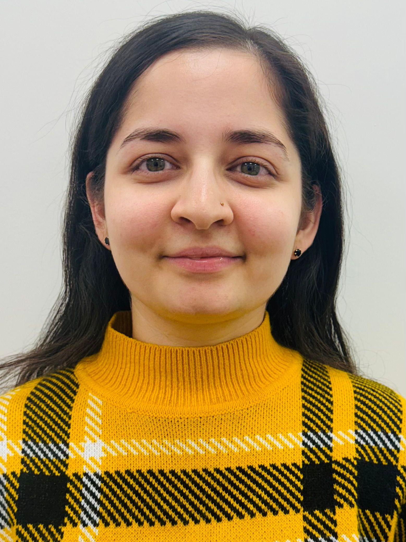 Vaibhavi wearing a yellow plaid sweater smiles for the camera