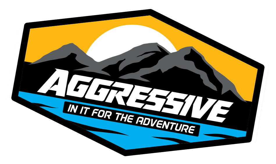 A logo for aggressive in it for the adventure with mountains and the sun.