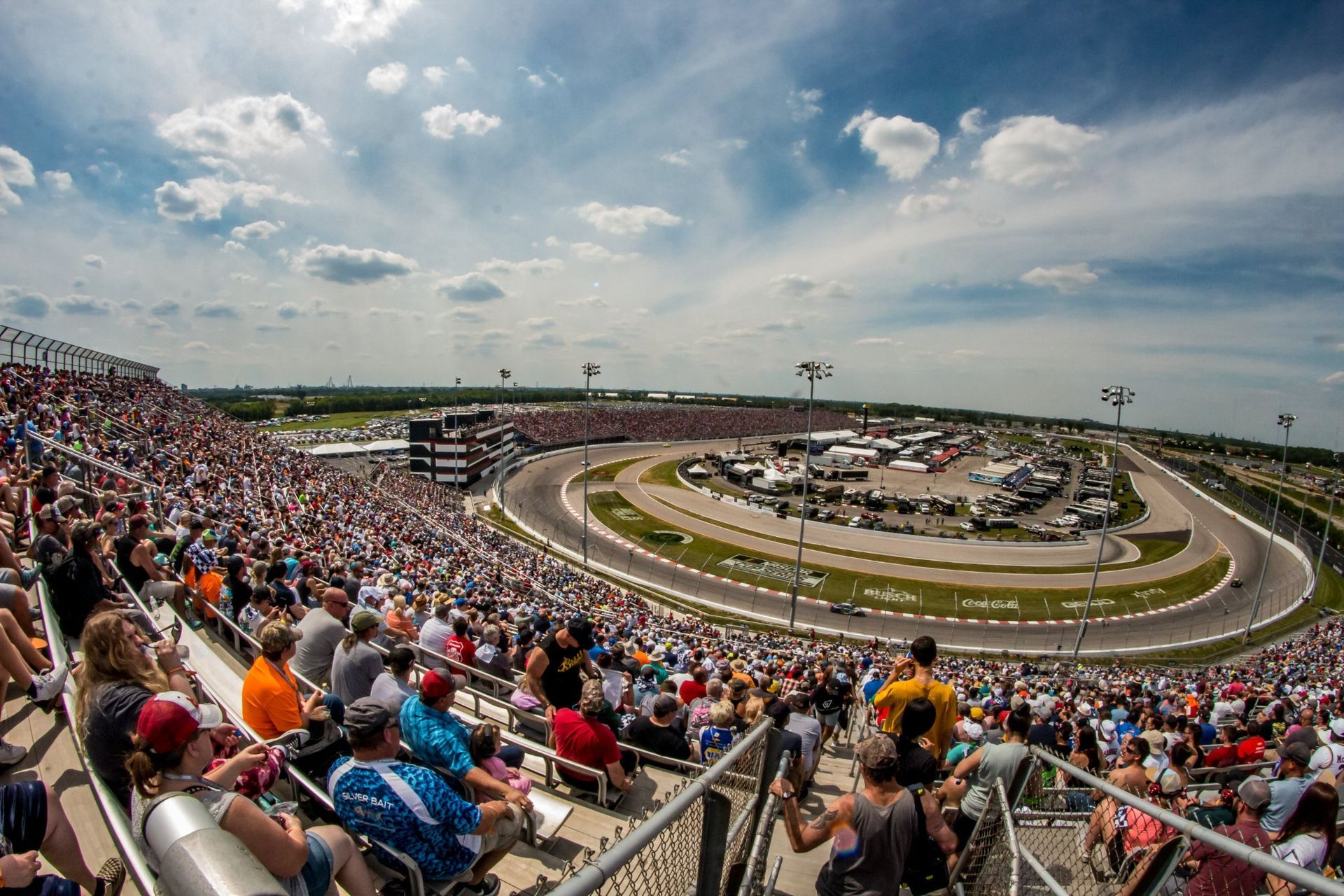 A large crowd of people are watching a race at a race track.