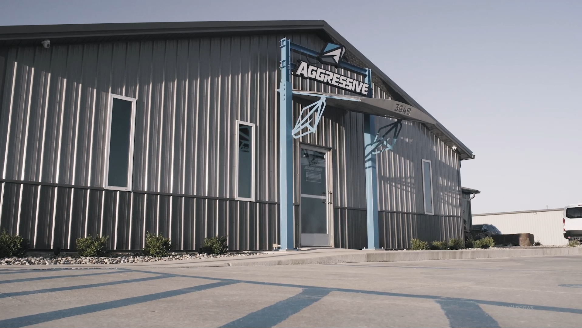 A large building with a lot of windows is sitting in a parking lot.