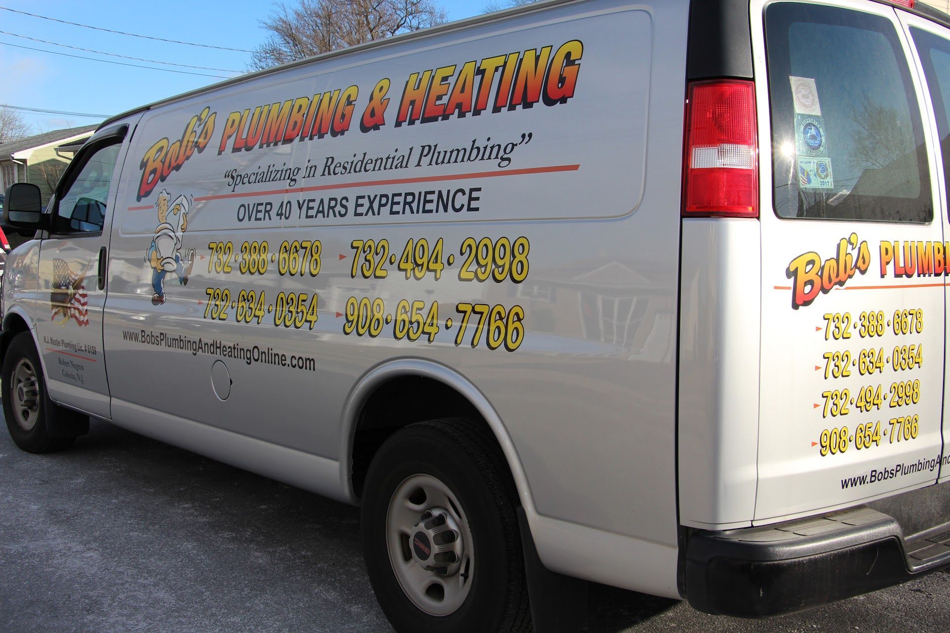Silver and white Bob's Plumbing & Heating van with company logo, phone numbers, and website parked outside.