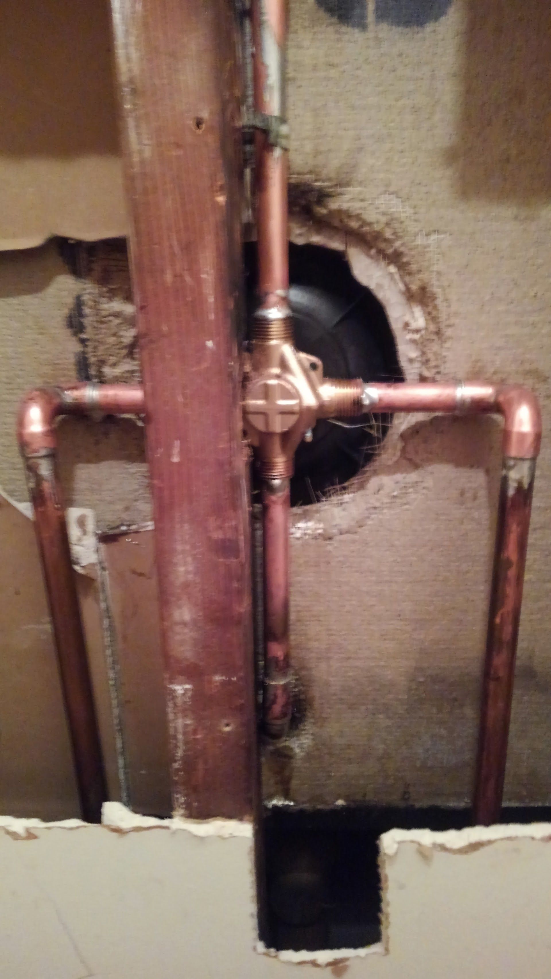 Copper plumbing pipes in a wall, likely for a shower valve.