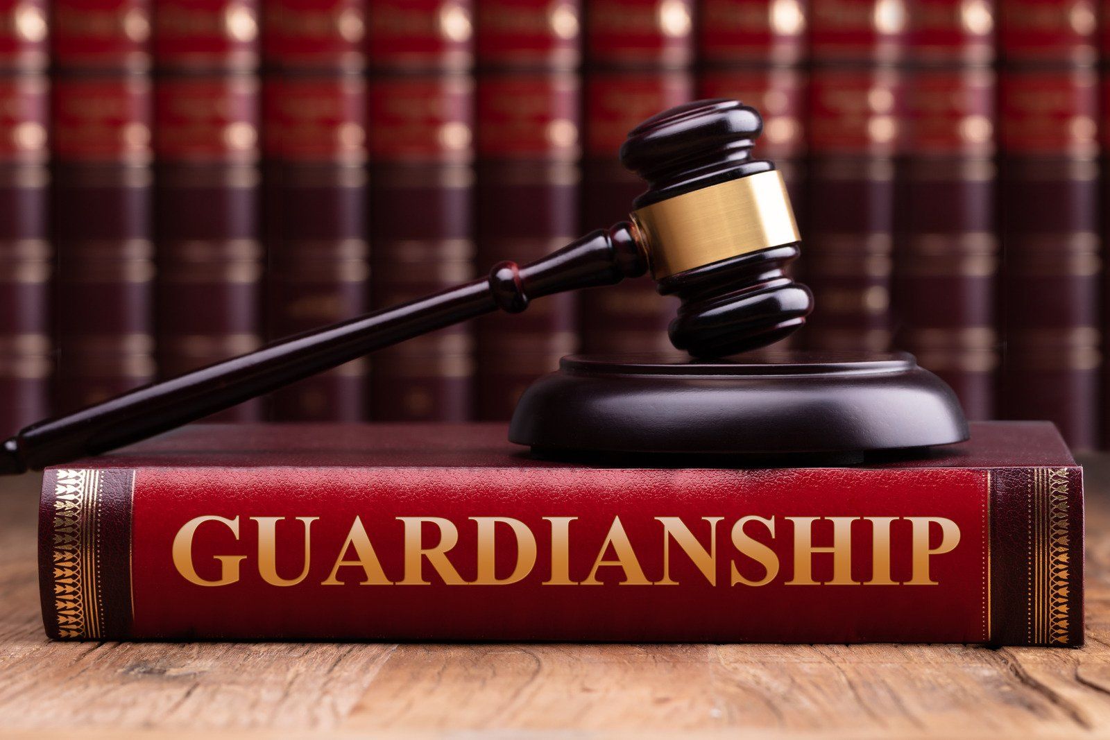 A judge 's gavel is sitting on top of a red book titled guardianship.