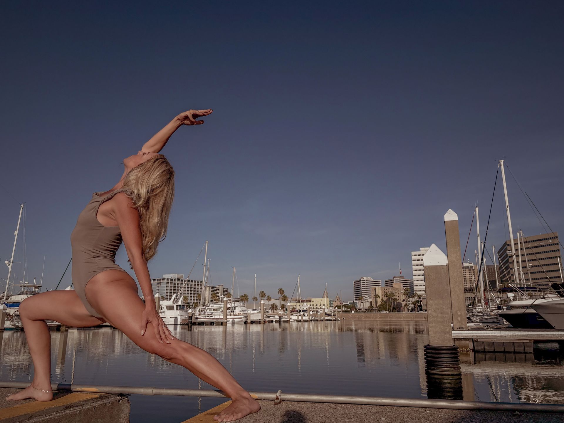 A woman in a bathing suit is doing a yoga pose in front of a body of water