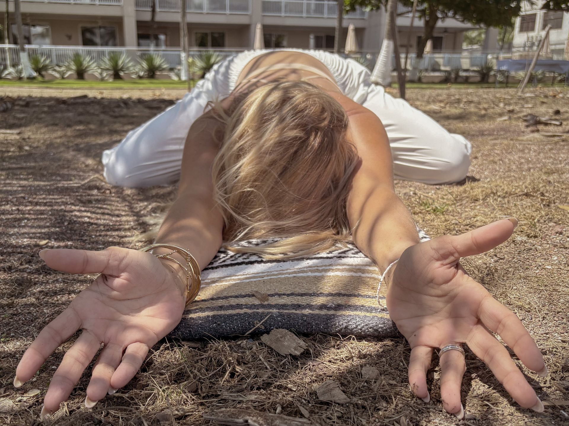 A woman is laying on the ground with her hands outstretched in a yoga pose.