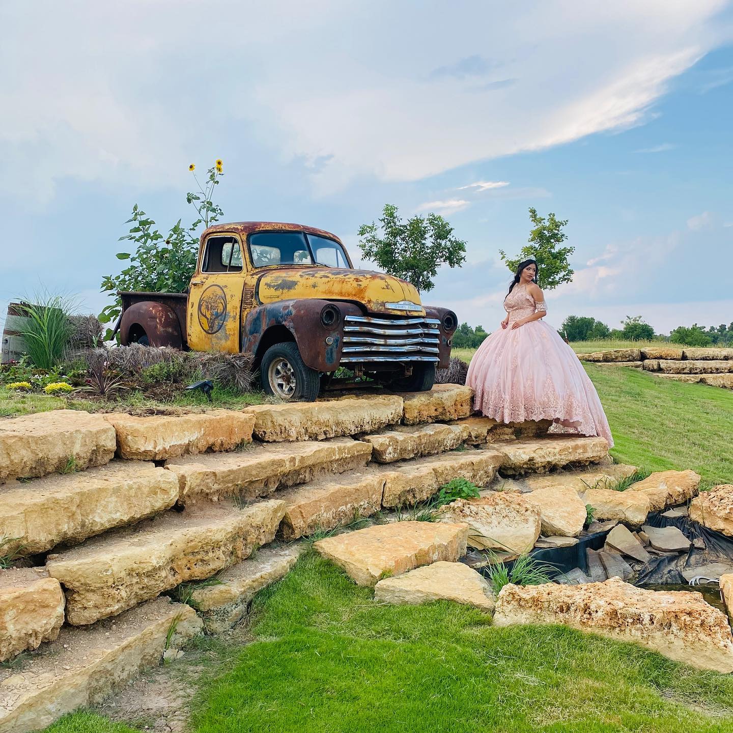 girl in pink ballgown posing next to old truck