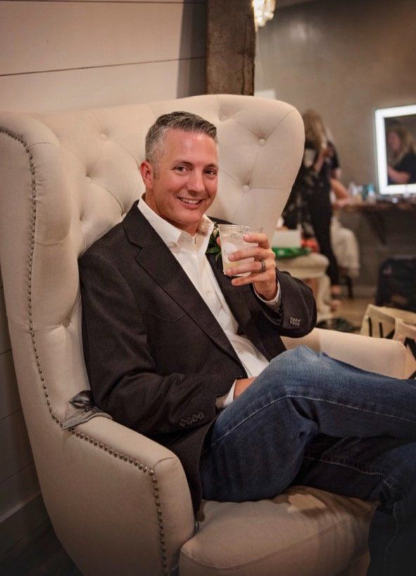 groomsman holding glass of water and smiling for photo