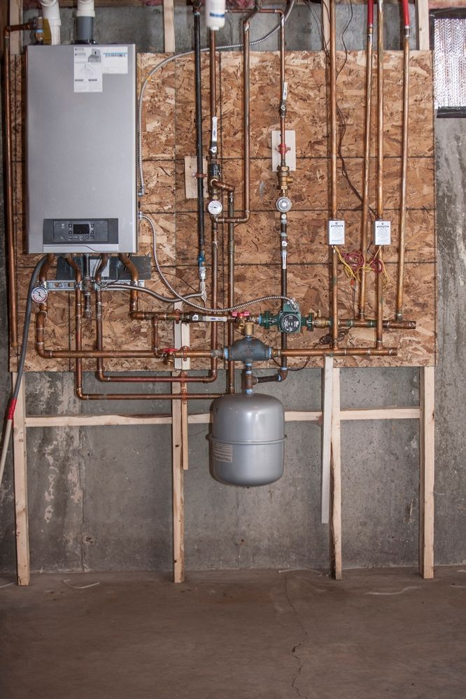 A water heater is sitting in a room next to a brick wall.