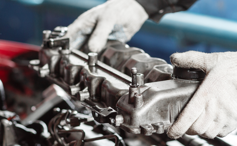 A person is working on a car engine in a garage | Cincinnati Transmission Specialists & Sharon Woods Auto Care