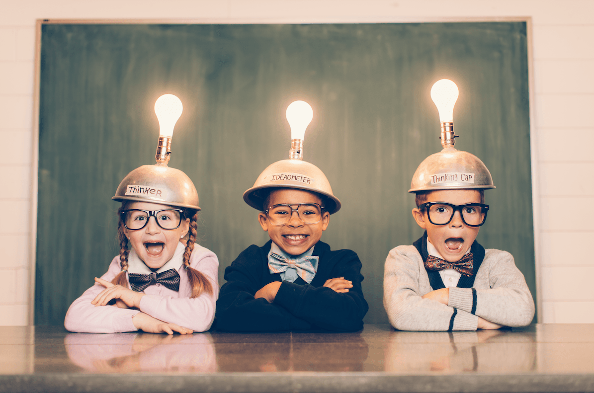 Three children are sitting at a table with light bulbs on their heads.