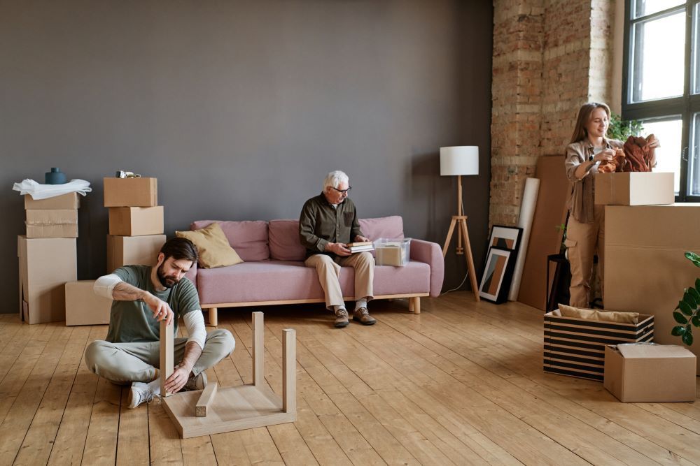 A man is sitting on the floor working on a table in a living room.