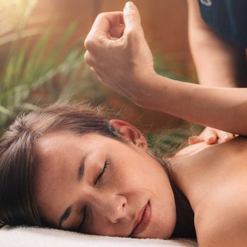 A woman is laying on a bed getting a massage.