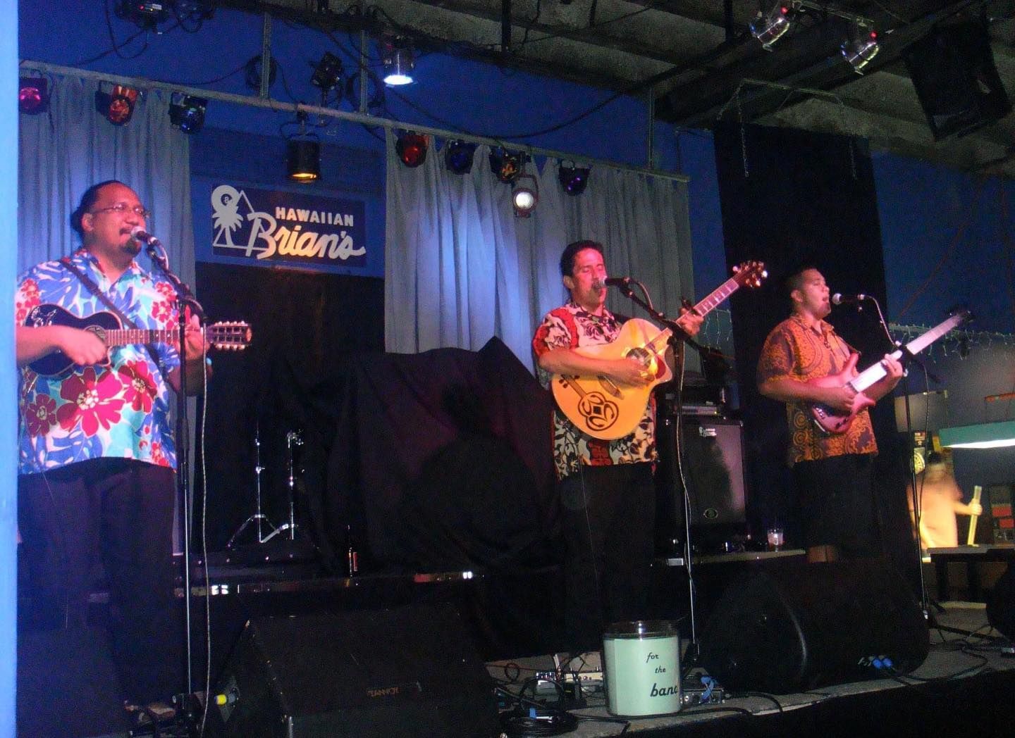 A group of men are playing instruments on a stage in front of a sign that says ' batani '