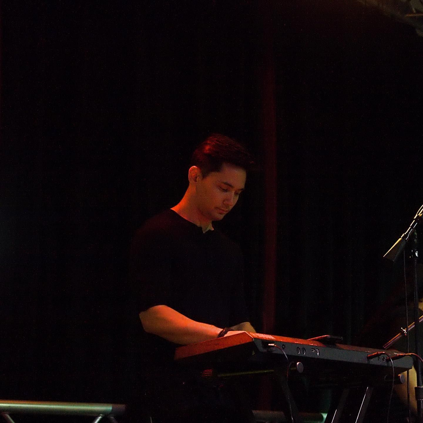 A man is playing a keyboard in a dark room