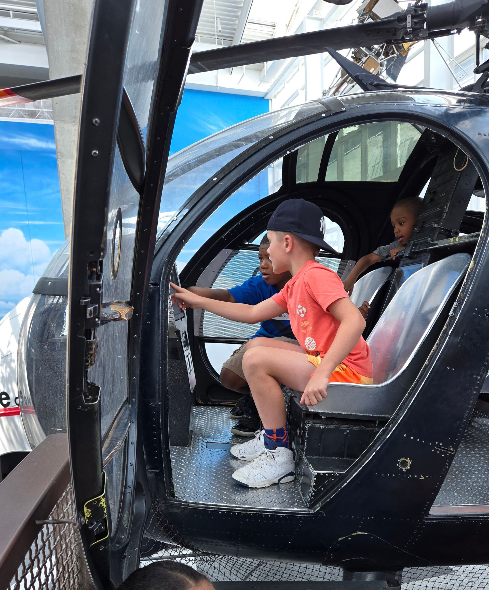 A boy in a red shirt is sitting in a helicopter