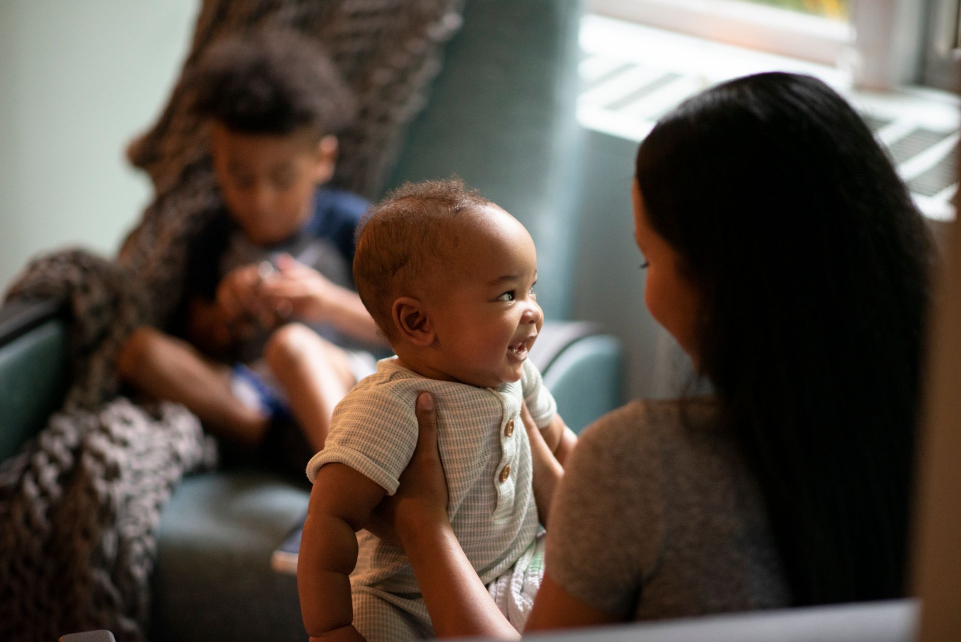 A woman is holding a baby in her arms while sitting on a couch.