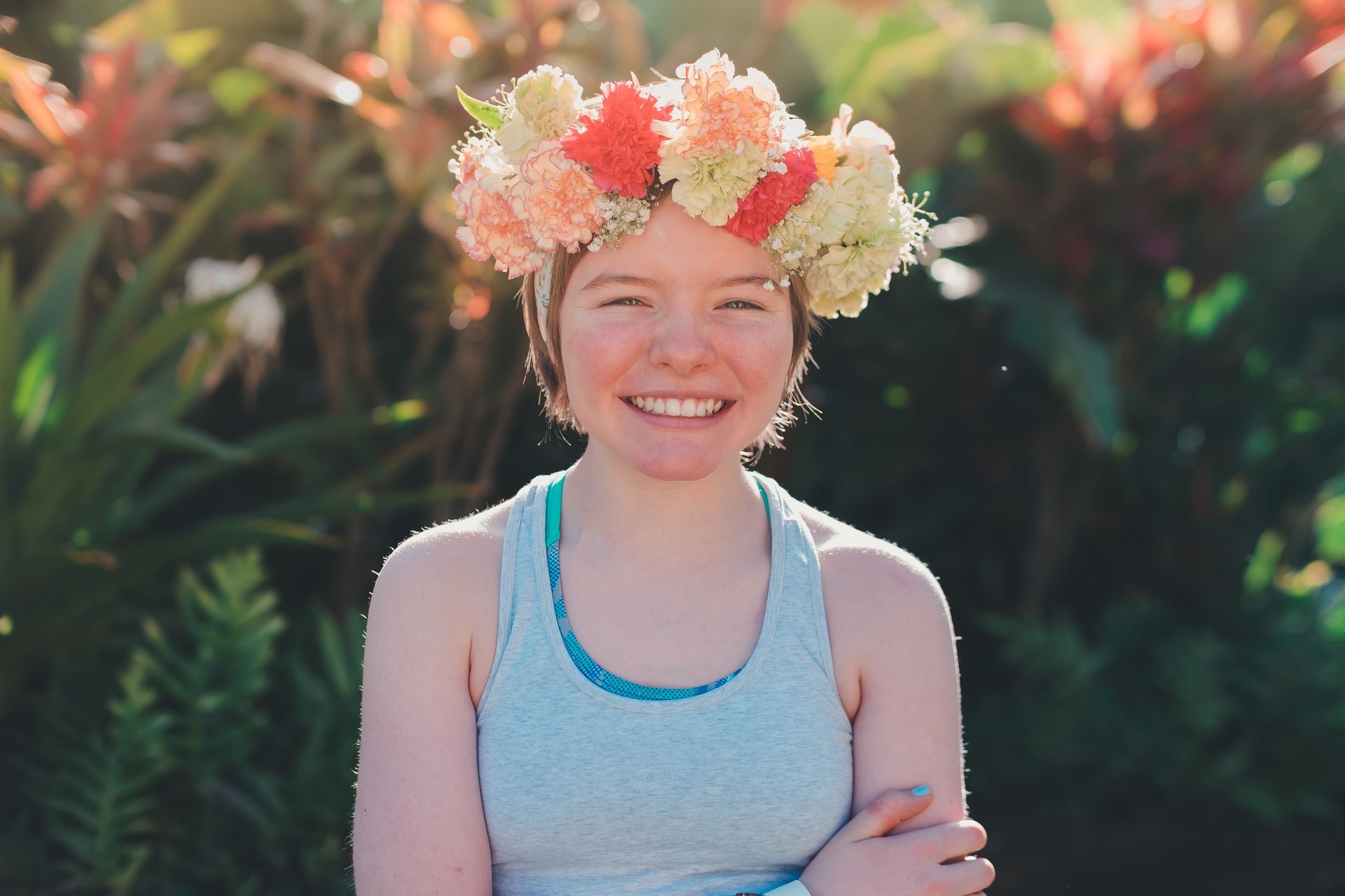 A young woman wearing a flower crown on her head is smiling.