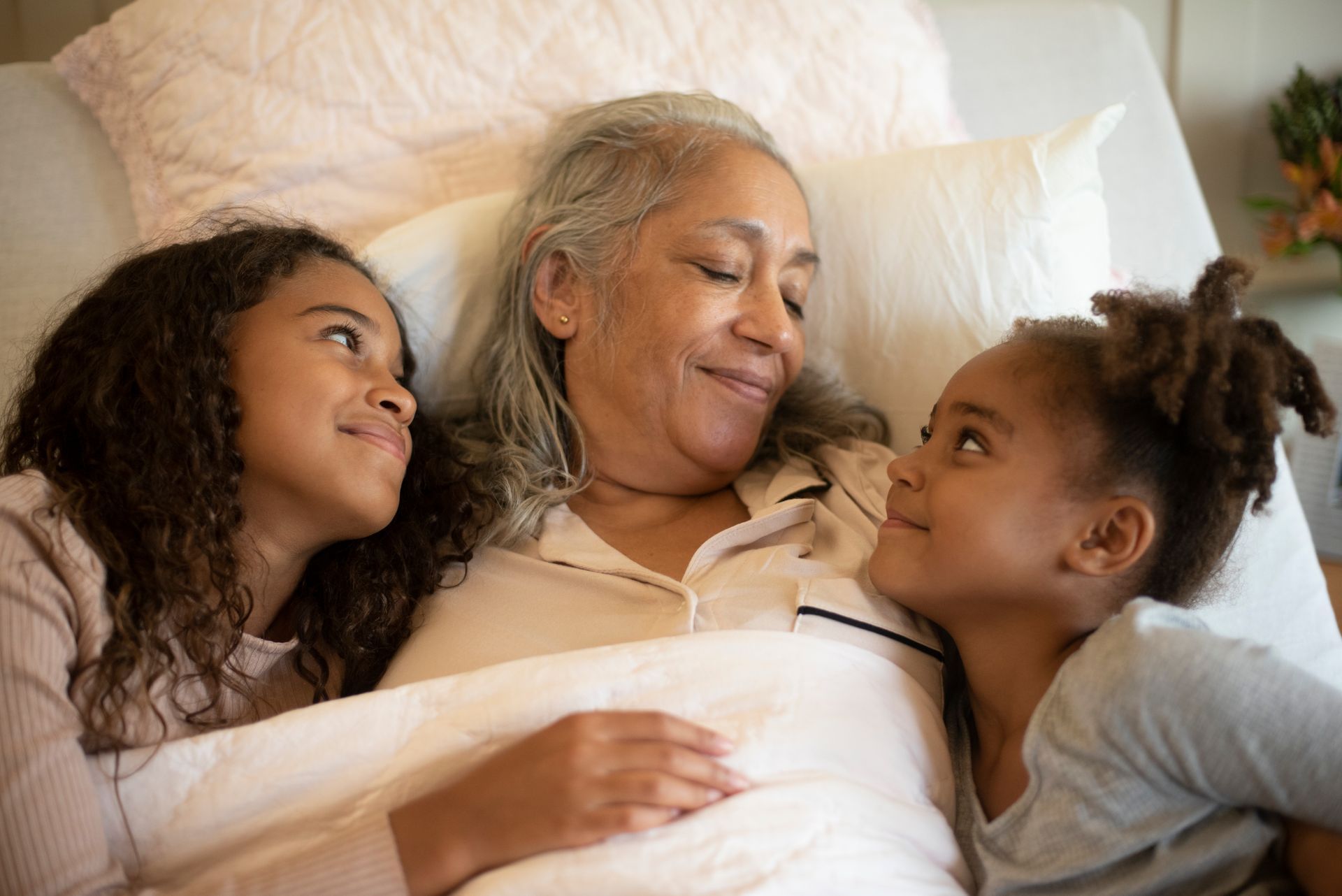 woman snuggling in bed with two girls