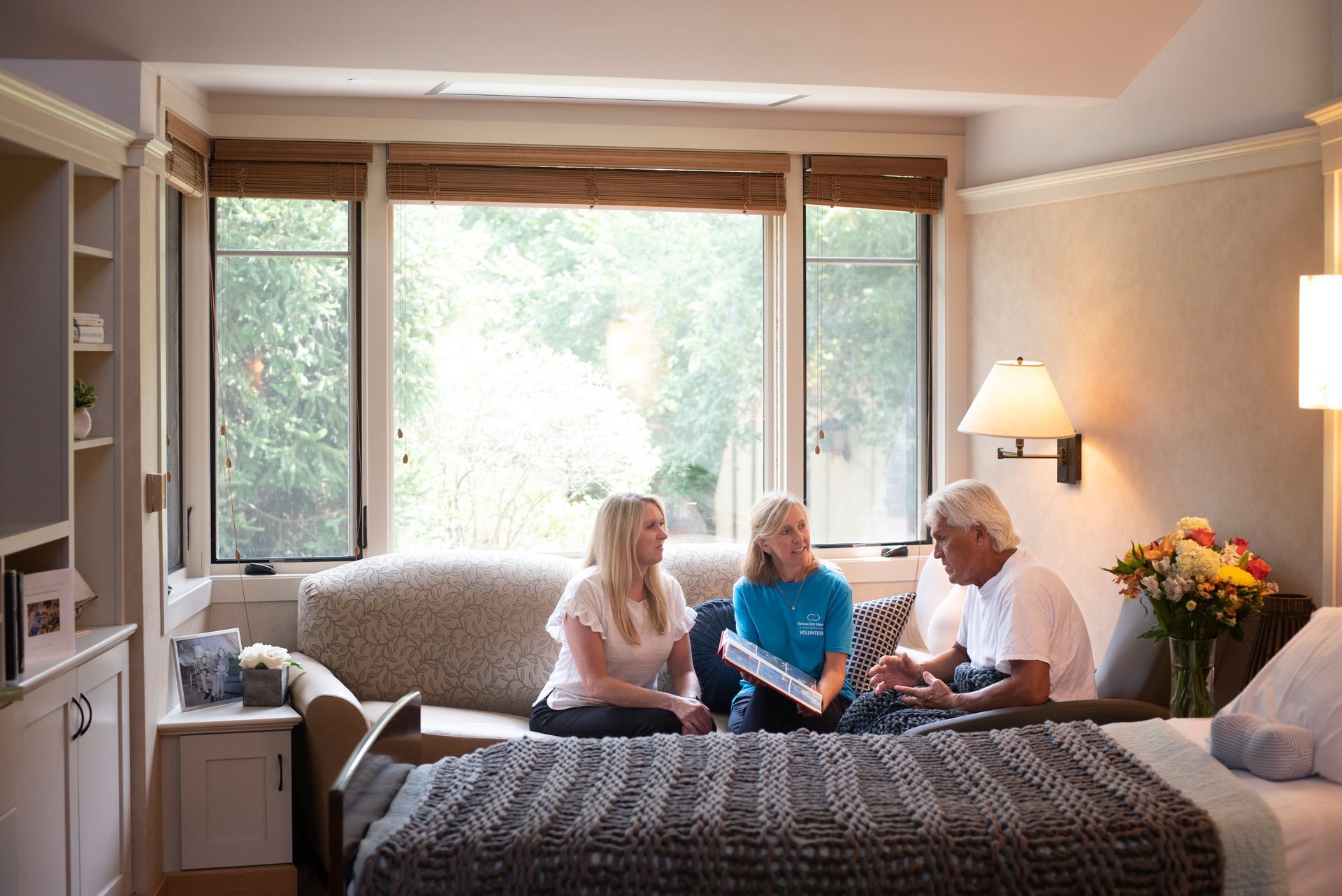 A man and two women are sitting on a couch in a hospital room.