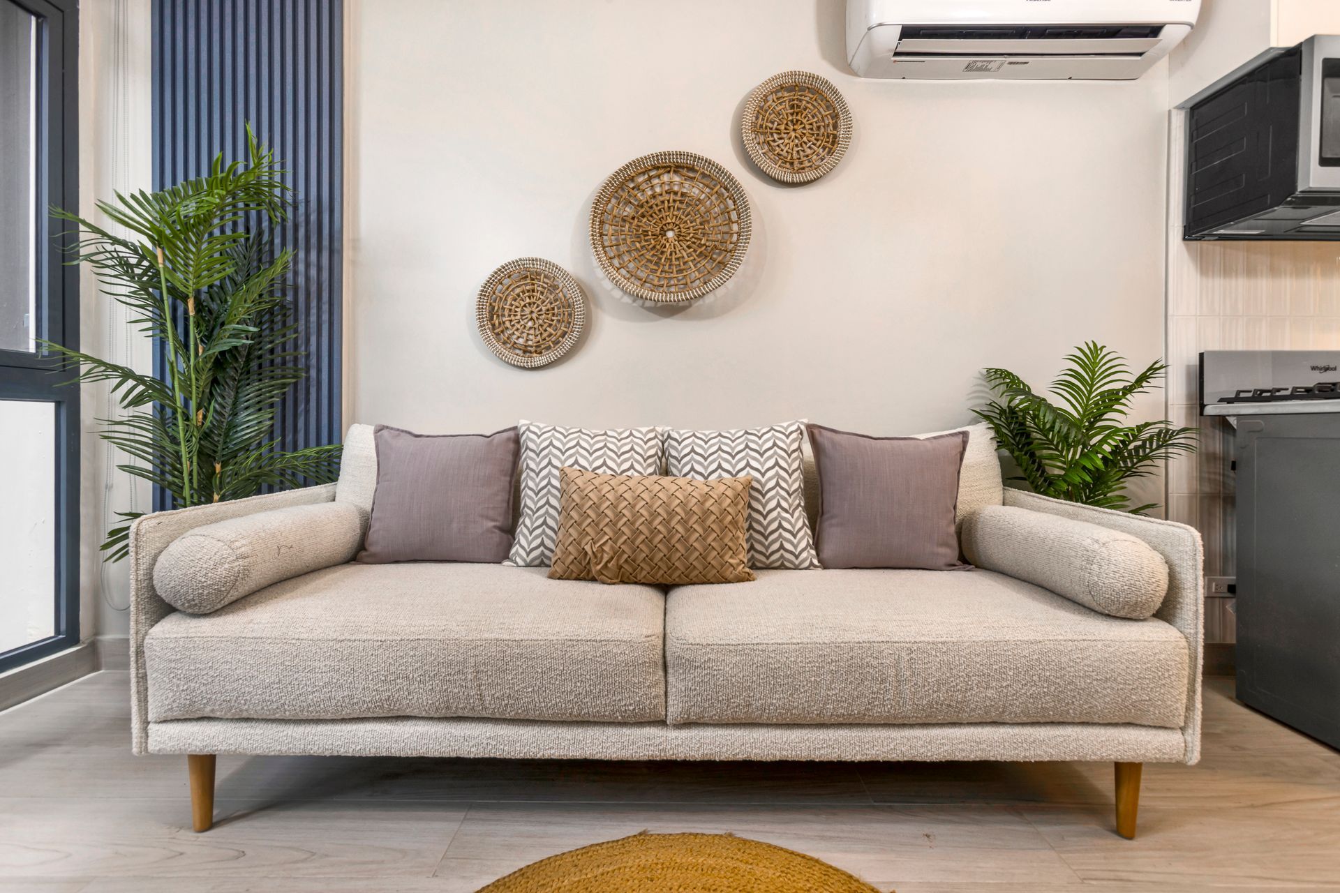 Beige sofa with decorative pillows, plants, and wall decor.