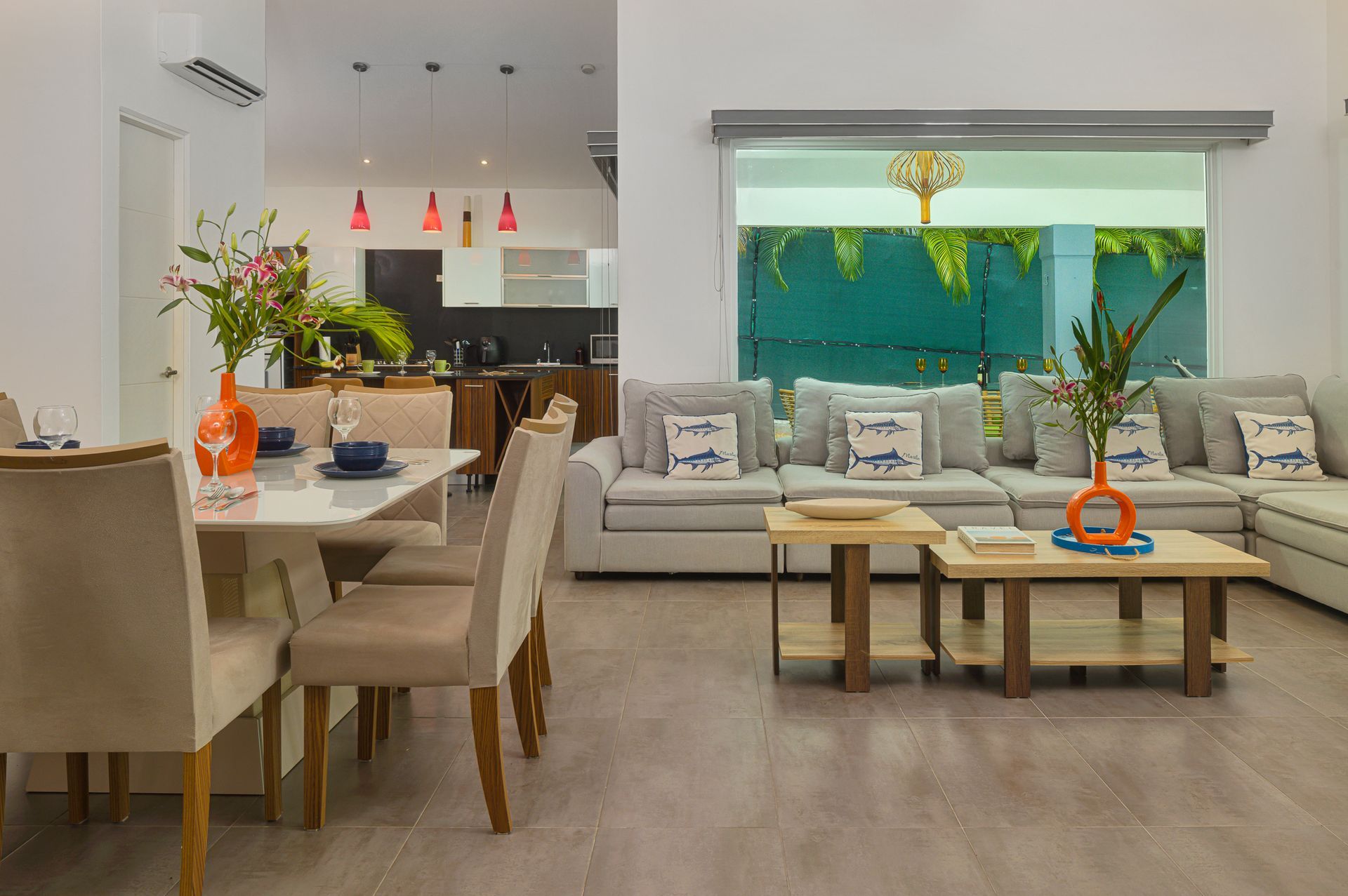 Modern open-plan living and dining area with gray sofa, table, and kitchen in the background.
