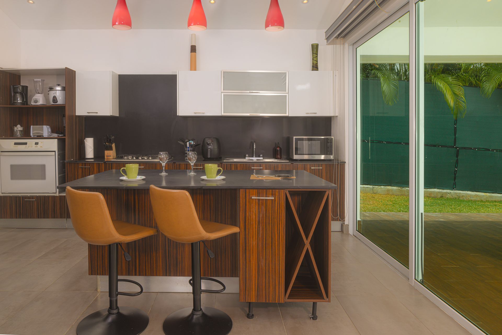 Modern kitchen with island, bar stools, and outdoor view.
