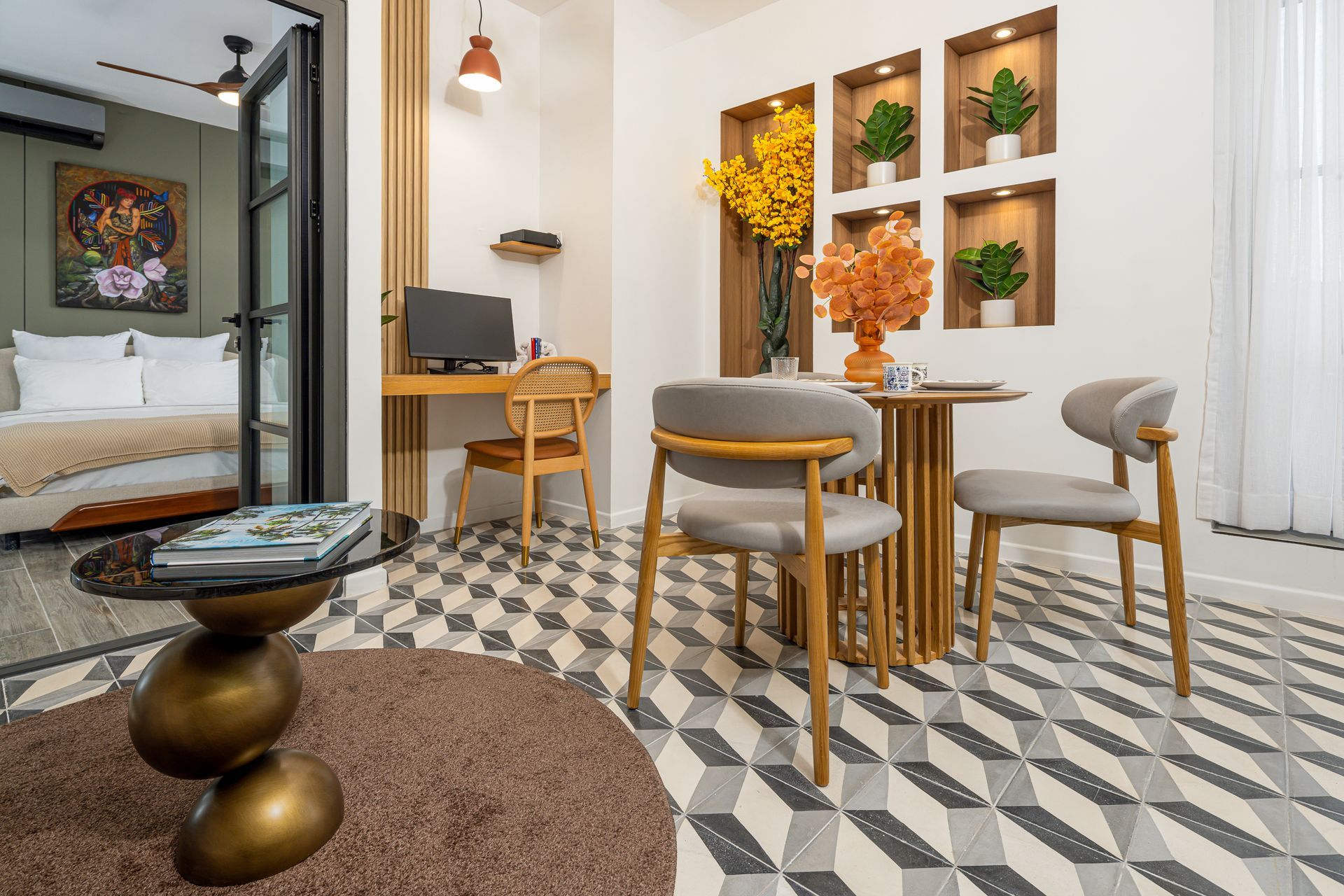 A modern dining area with table, chairs, desk, and a bedroom visible. The floor has a geometric pattern. real estate photos by ivan marquez panama