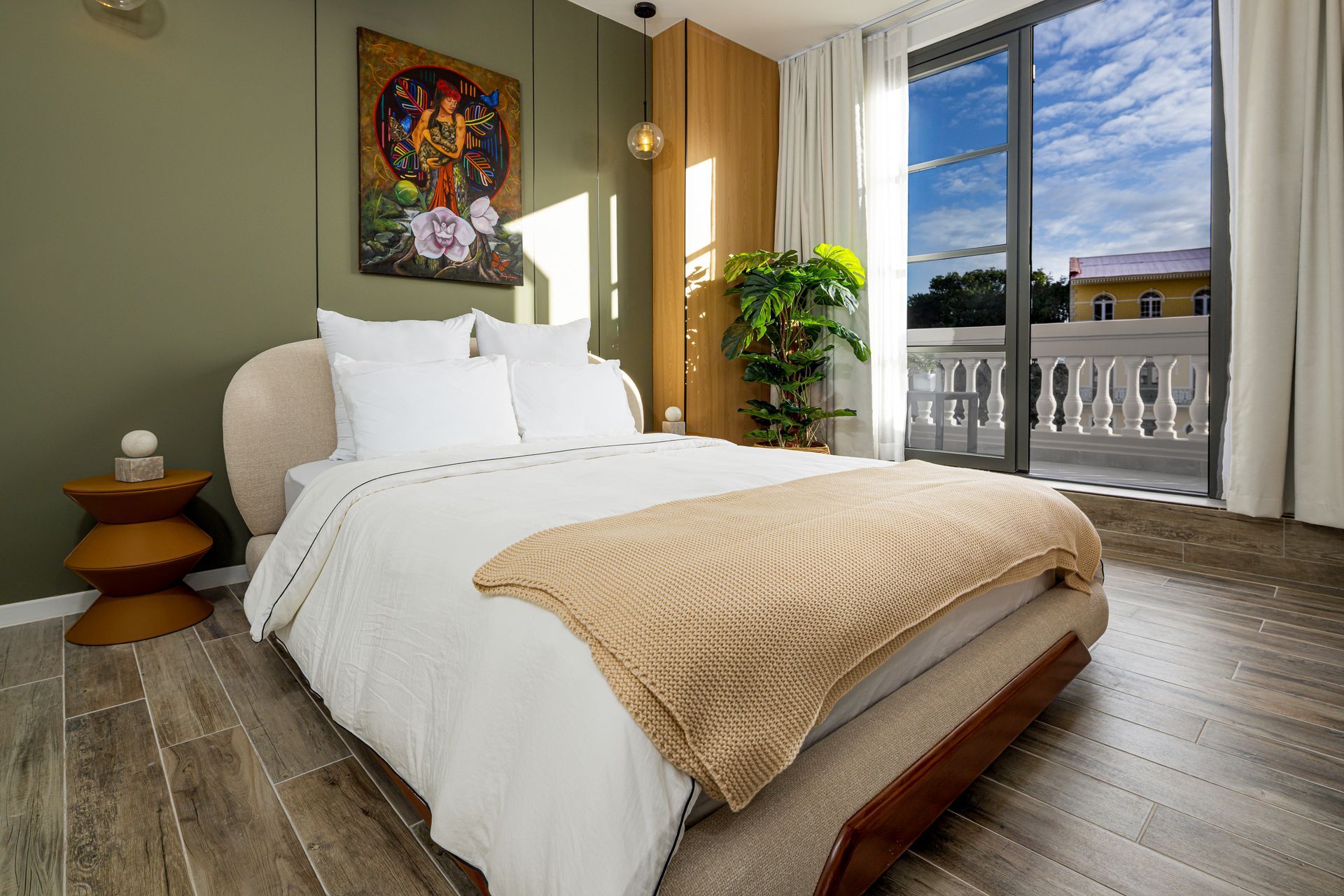 Bedroom with bed, art, balcony, and view of a building with white columns. real estate photos by ivan marquez panama