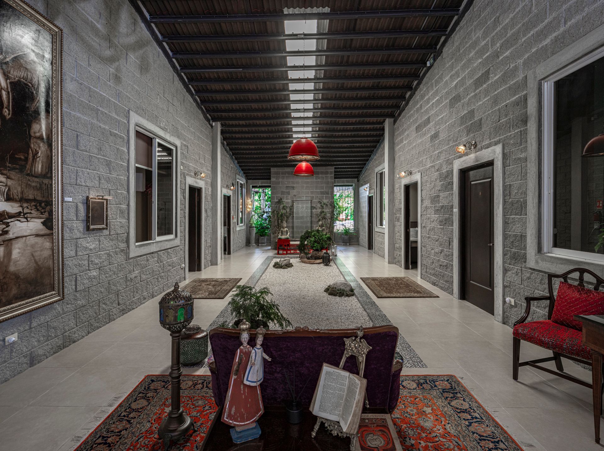 Long hallway in a building with stone walls, brown ceiling, red accents, and decorations.