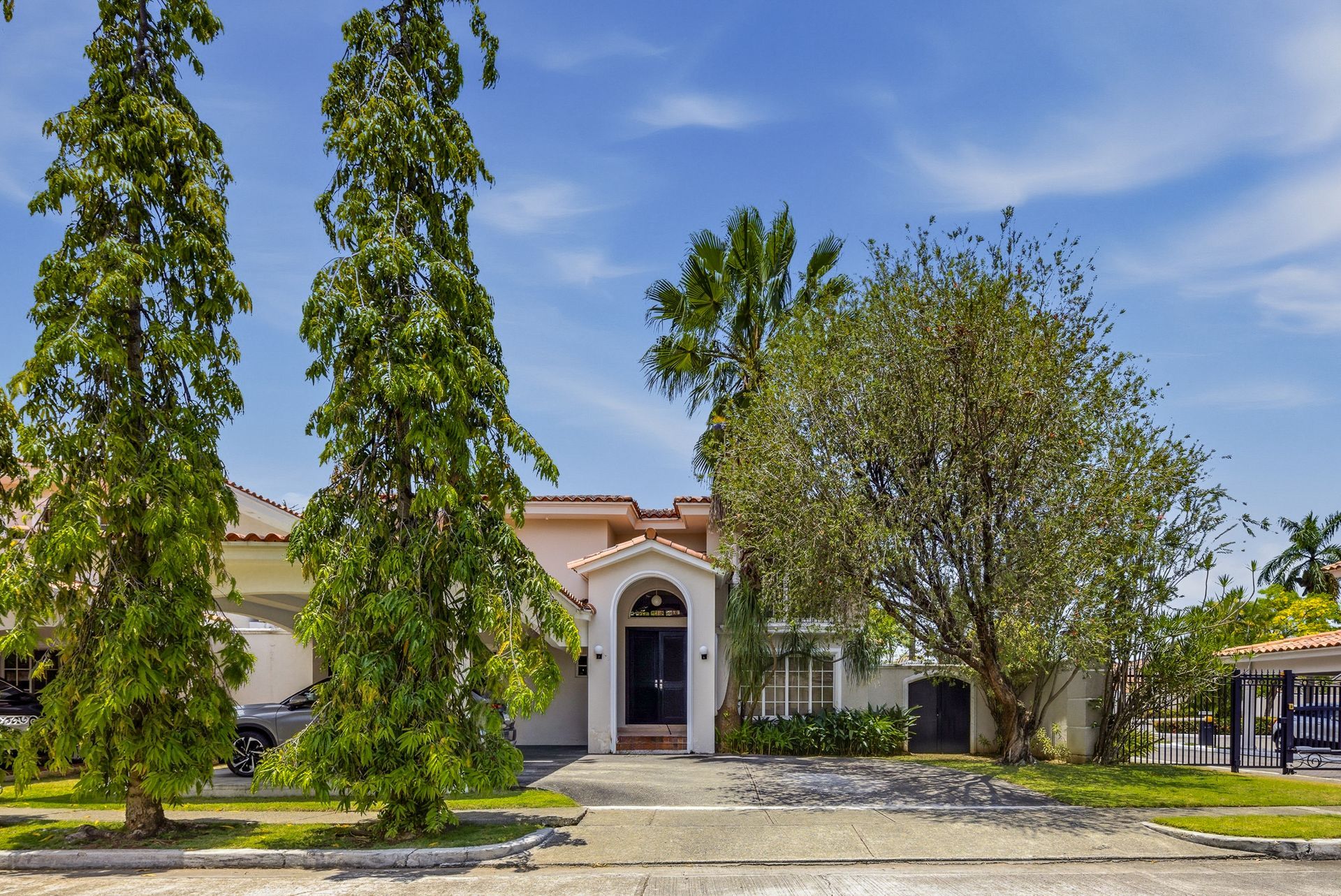 Costa del Este luxury home front facade with Mediterranean architecture and mature landscaping, Panama City real estate.